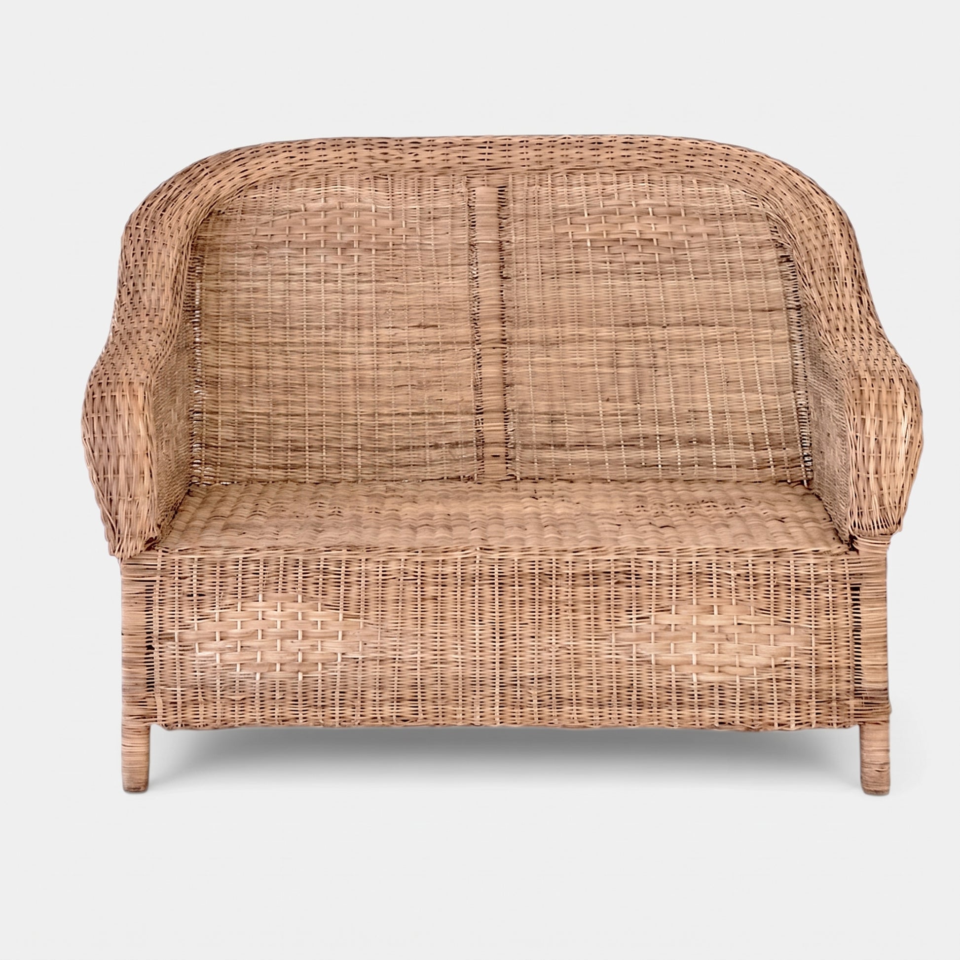 A natural woven rattan loveseat sofa with a curved backrest and armrests, shown from the front against a light gray background.