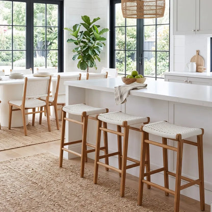 Modern kitchen with white island, wooden stools, and large windows.