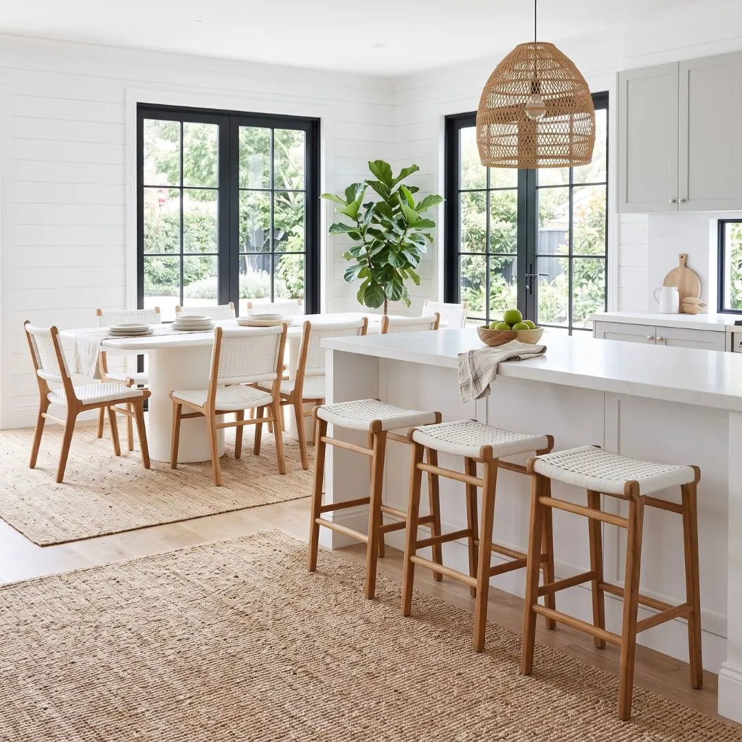Modern kitchen with white island, wooden chairs, and a plant