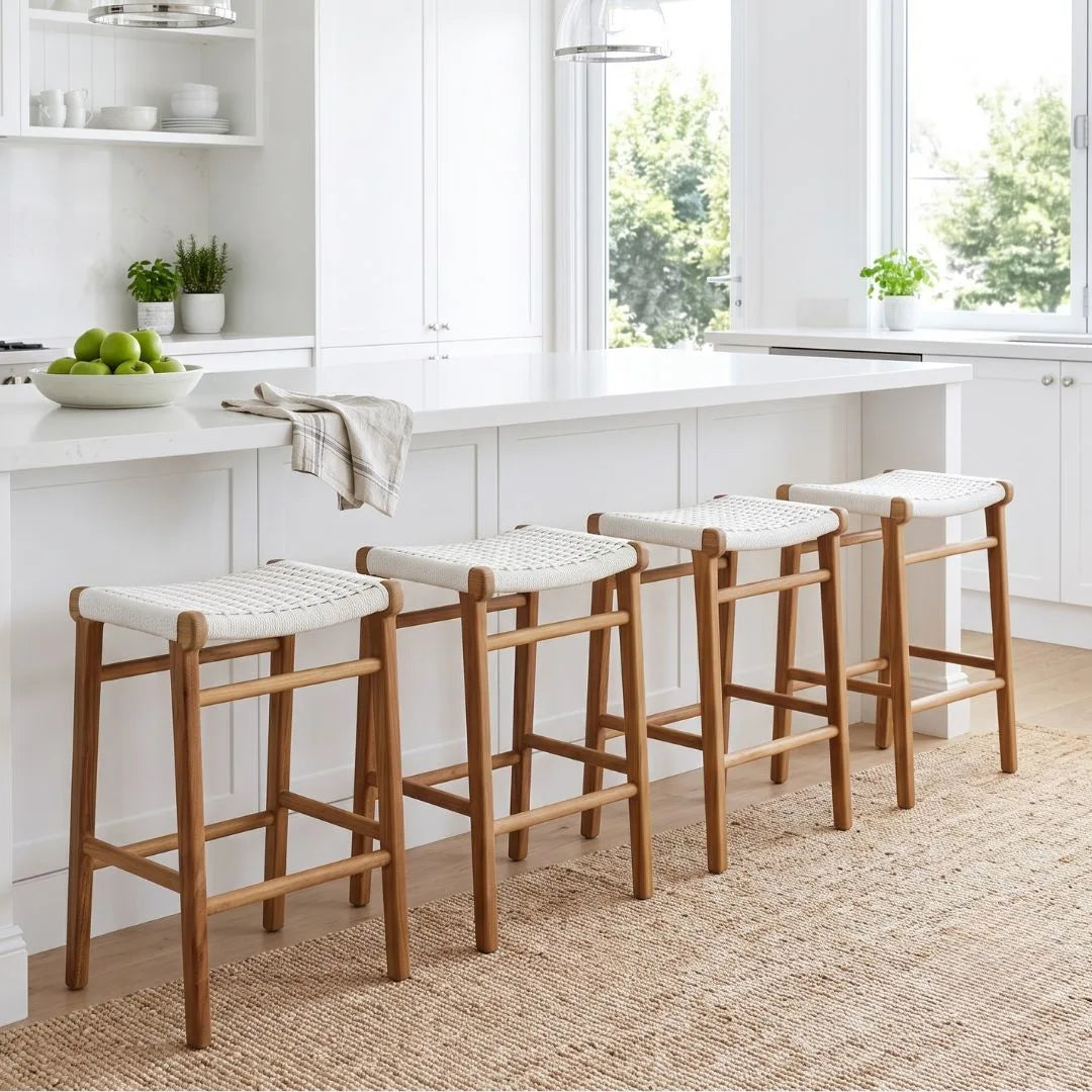 Four wooden bar stools with white seats in a kitchen setting.