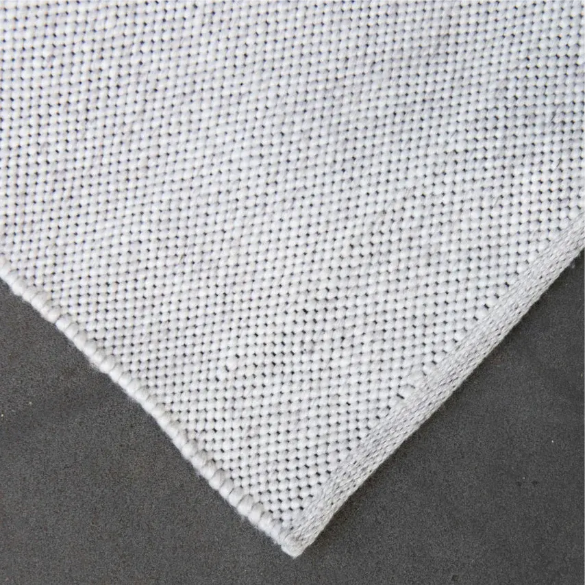 Close-up of a textured off white eco floor mat on a dark background