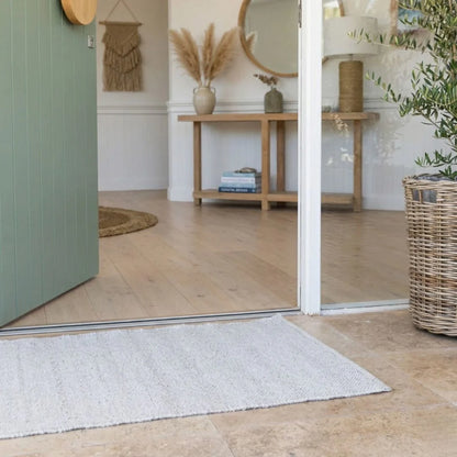 Front door entry way with wooden floor, eco rug, and decorative elements.