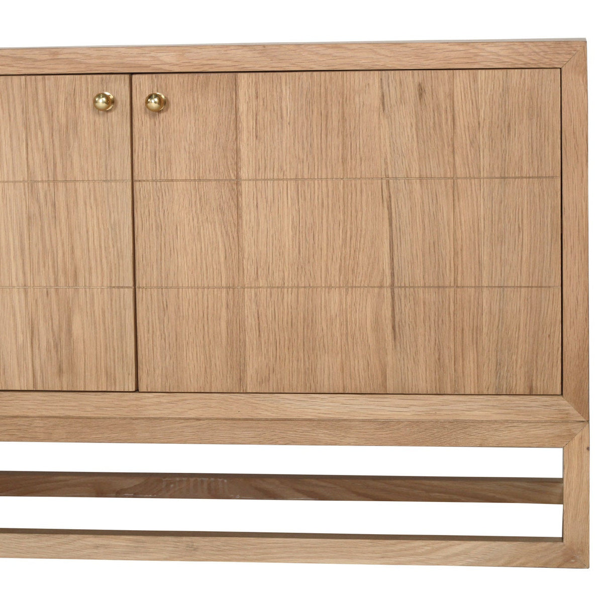 A close-up of a light oak wood cabinet with two doors, featuring a grid pattern of recessed panels and small round brass knobs, set against a plain white background.