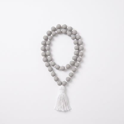 A double-strand beaded necklace with matte gray round beads and a white tassel, displayed on a clean white background.