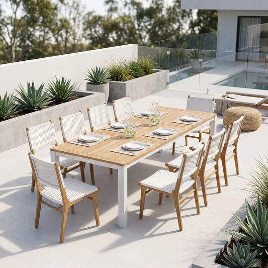 An outdoor dining set on a modern patio, featuring a rectangular light wood table with white legs and eight matching chairs with woven white seats and backs.