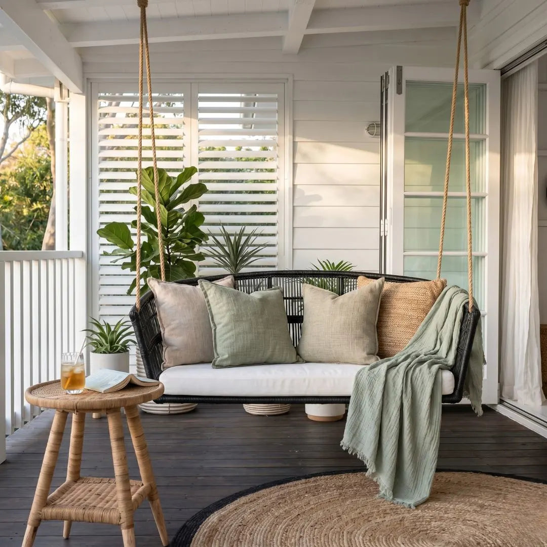 Outdoor patio with a swing, cushions, and a small table on a wooden deck.