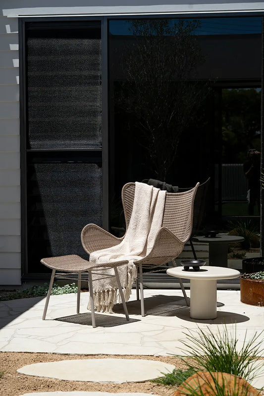 Woven chair with a blanket on it in an outdoor setting