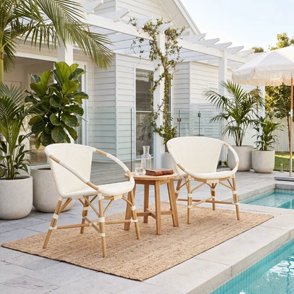 A 3-piece outdoor patio furniture set featuring two cream mesh sling chairs with natural wood frames and a matching small wooden side table, arranged on a jute rug next to a swimming pool.