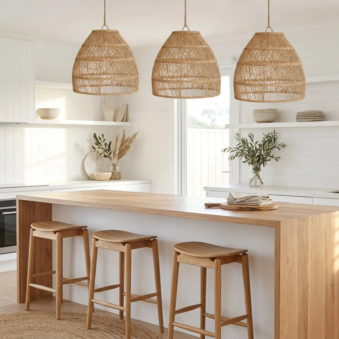 Modern kitchen with wooden island, stools, and wicker pendant lights.