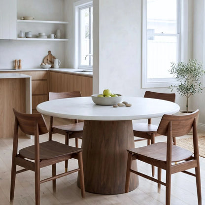 Jansen microcement round dining table with walnut base, matching walnut jansen dining chairs in a modern home.