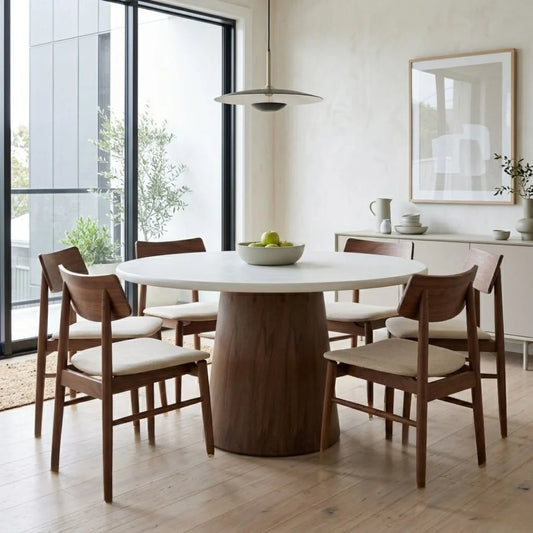Jansen microcement round dining table with walnut base, matching walnut jansen dining chairs in a modern home.