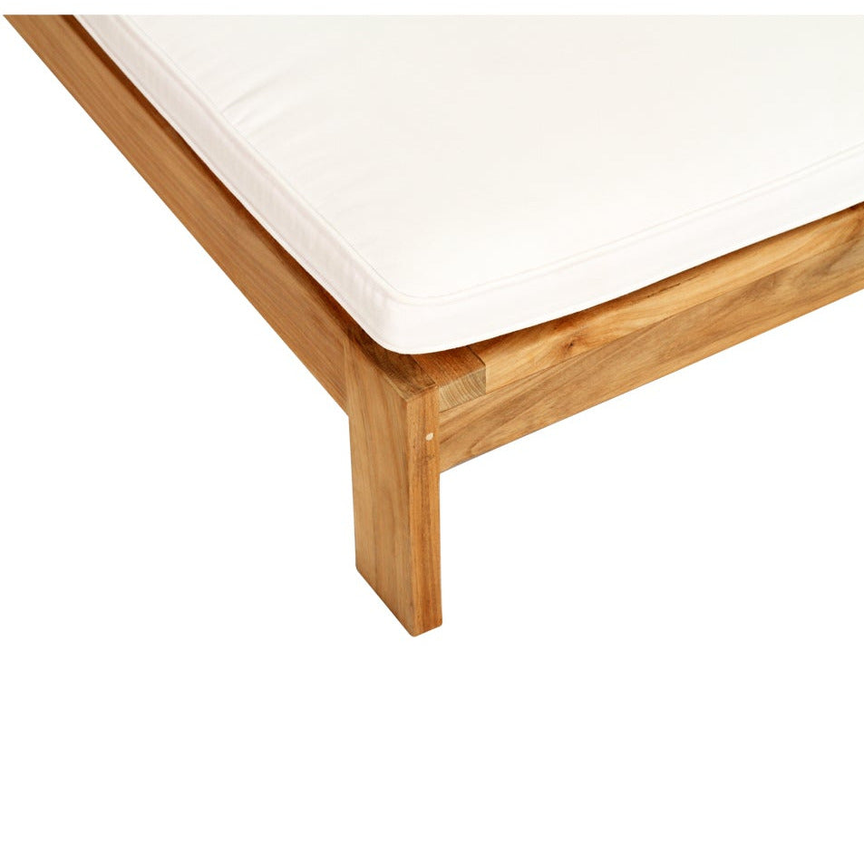 A close-up corner view of a wooden sunbed frame with a white mattress or cushion on a plain white background.