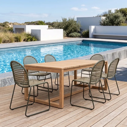 Outdoor dining set with a rectangular wooden table and six woven-back chairs on a wooden deck beside a swimming pool.