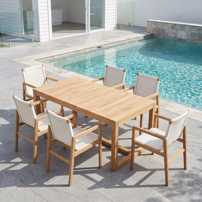 A 7-piece outdoor dining set consisting of a rectangular light oak table and six matching armchairs with cream woven sling backs and seats, arranged on a gray stone patio next to a swimming pool.