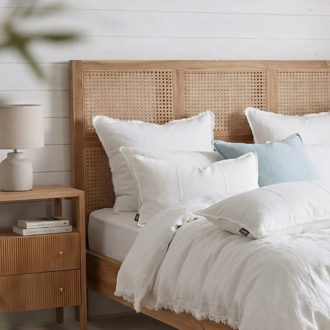 Bedroom with wooden headboard, white bedding, and nightstand with lamp.