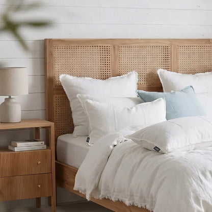 Bedroom with wooden headboard, white bedding, and nightstand with lamp.
