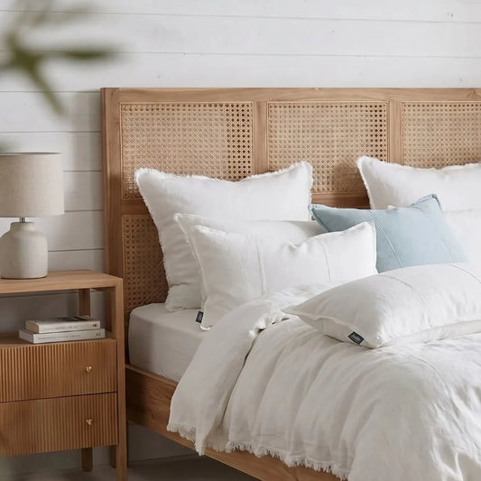 Bedroom with wooden headboard, white bedding, and nightstand with lamp.