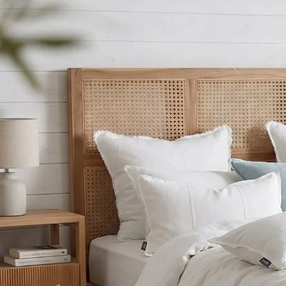 Bedroom with wooden headboard, white bedding, and nightstand with lamp.