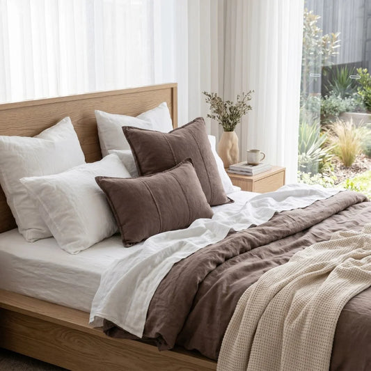 Bed with brown and white bedding in a bright bedroom