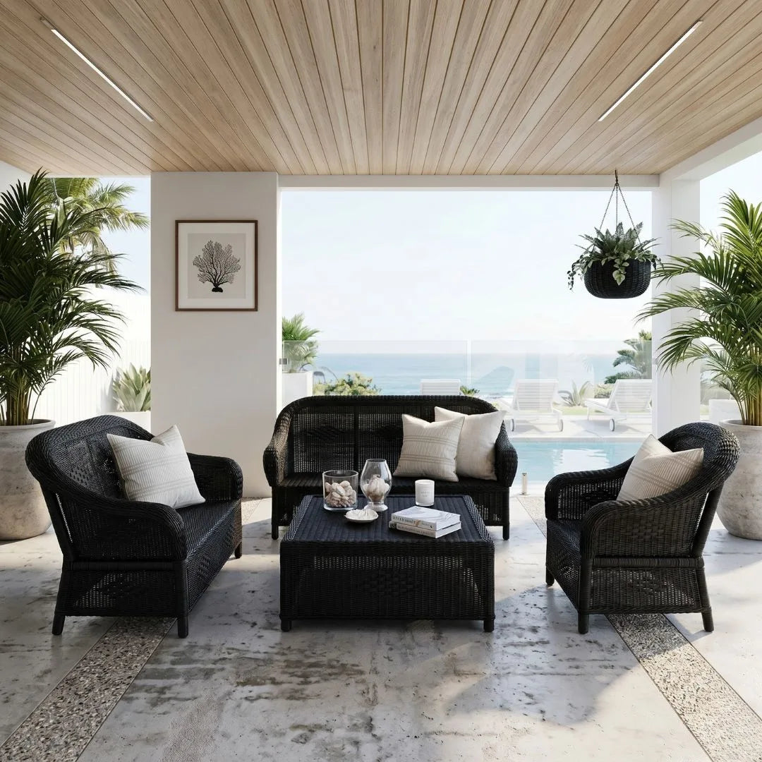 Outdoor patio with black wicker furniture, table, and white cushions in a modern setting.