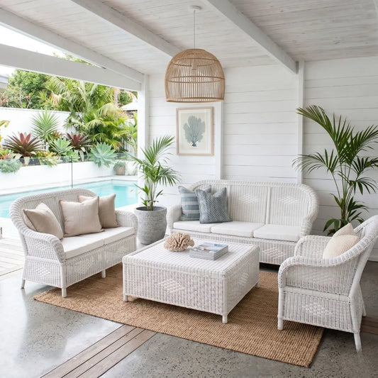 White wicker outdoor furniture set with cushions in a poolside setting.