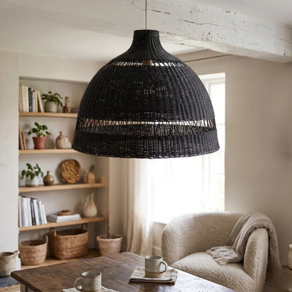 Black woven pendant light hanging in a living room with a sofa and bookshelf.