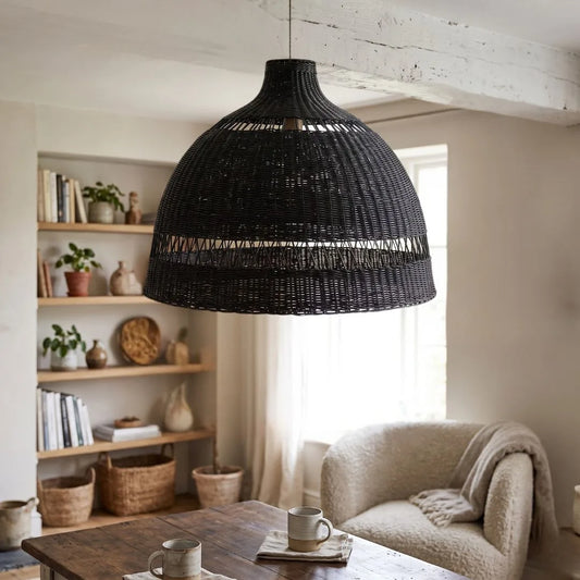 Black woven pendant light hanging in a living room with a sofa and bookshelf.