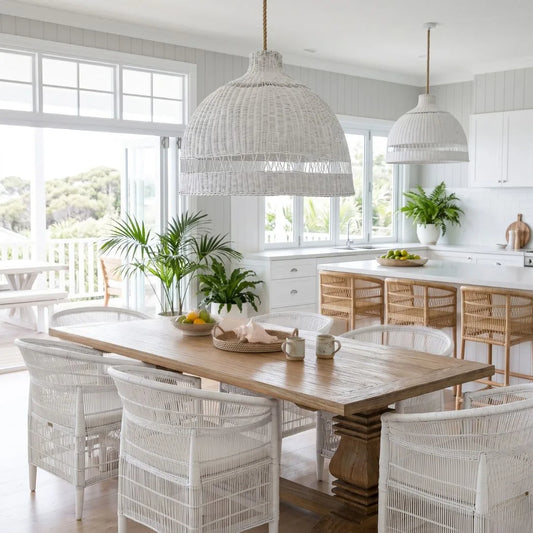 Dining area with wooden table and white wicker chairs in a bright kitchen.