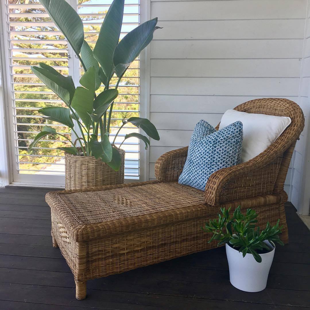 Wicker chair with cushions and plants on a wooden deck