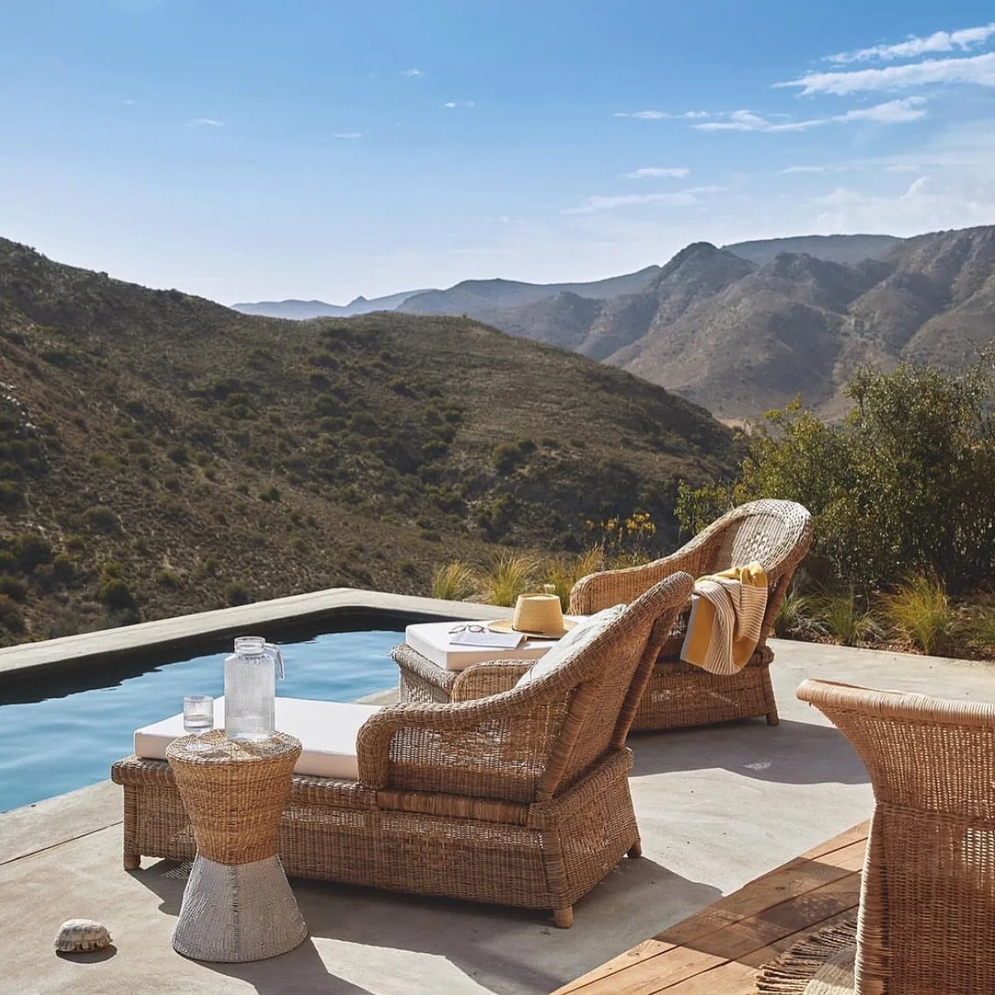 Wicker chairs by a pool with a scenic mountain view