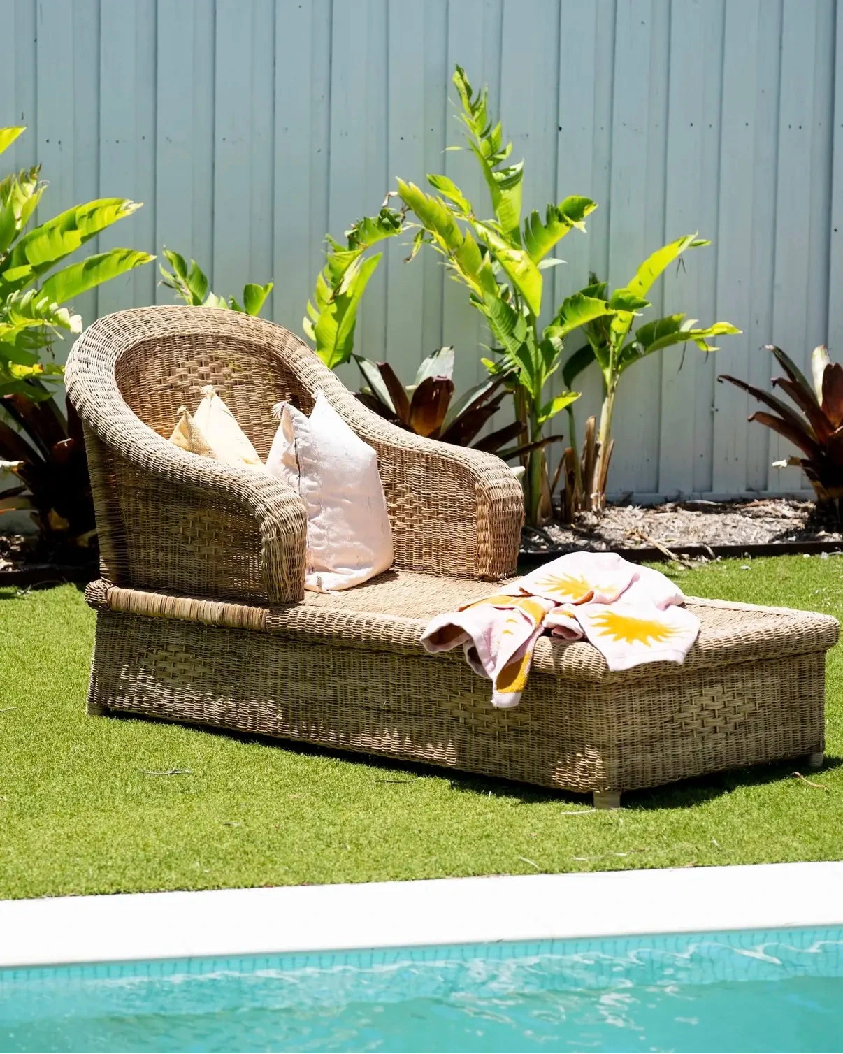 Wicker outdoor lounge chair with cushions by a poolside