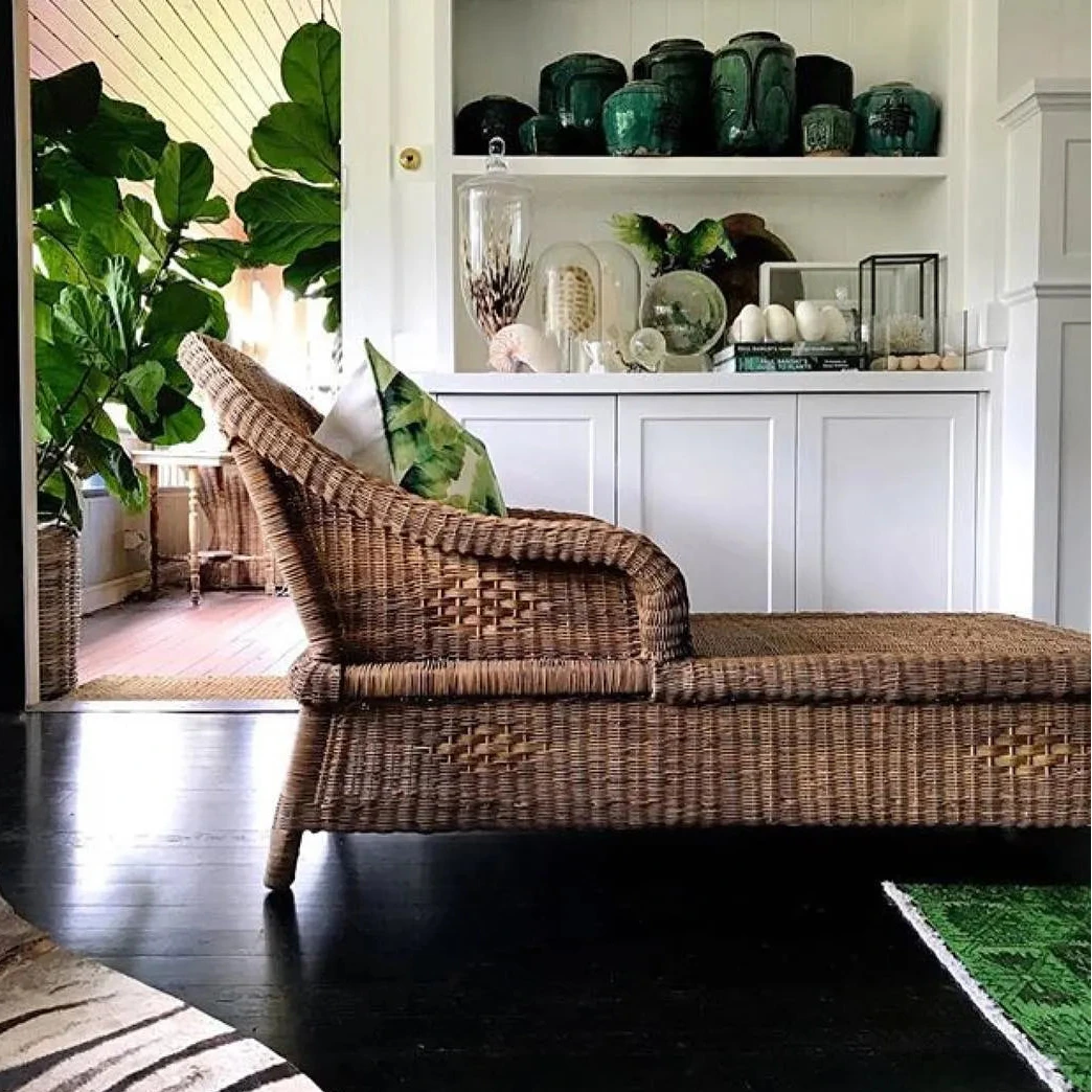 Wicker lounge chair in a stylish living room with green decor elements.