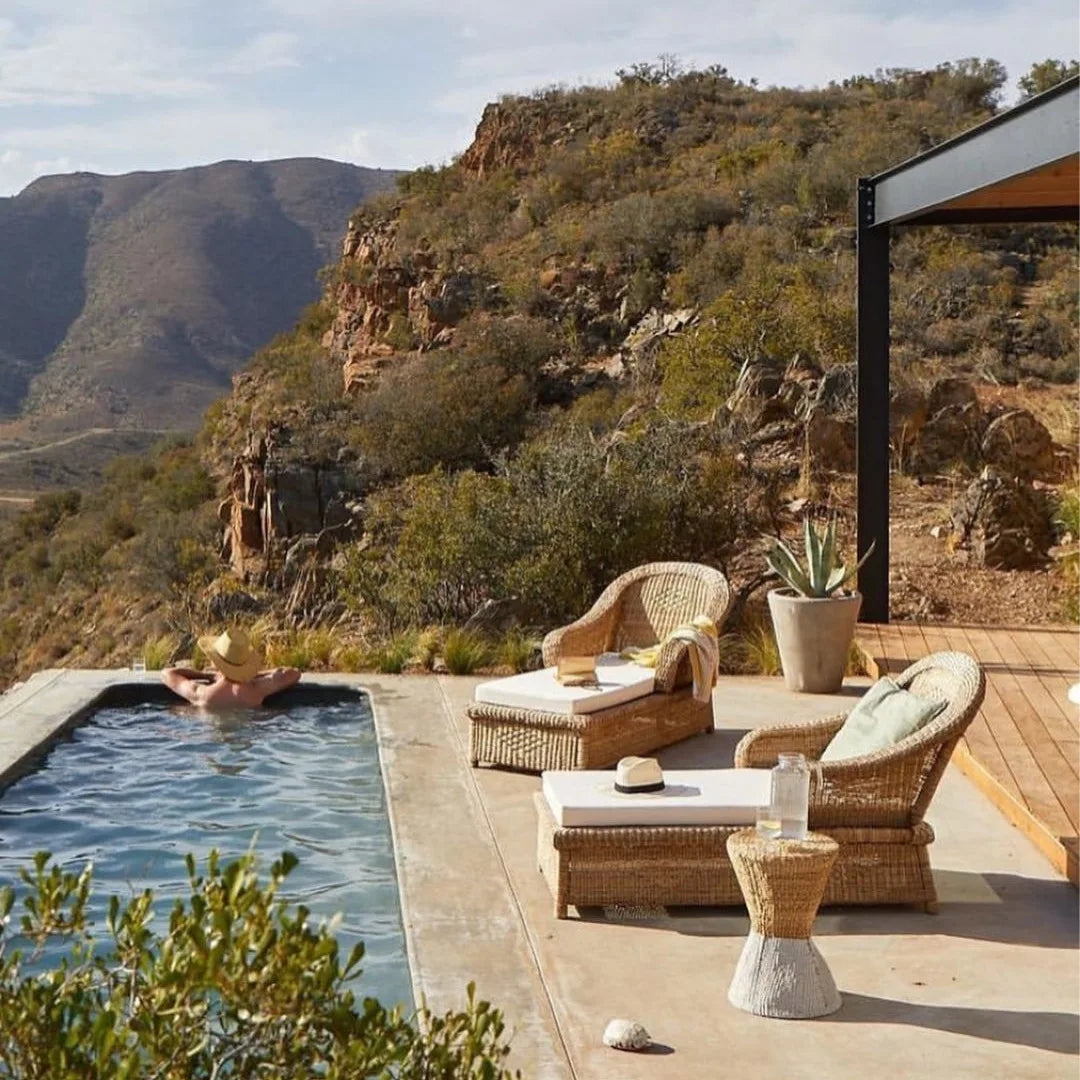 Outdoor pool area with wicker furniture and scenic mountain view