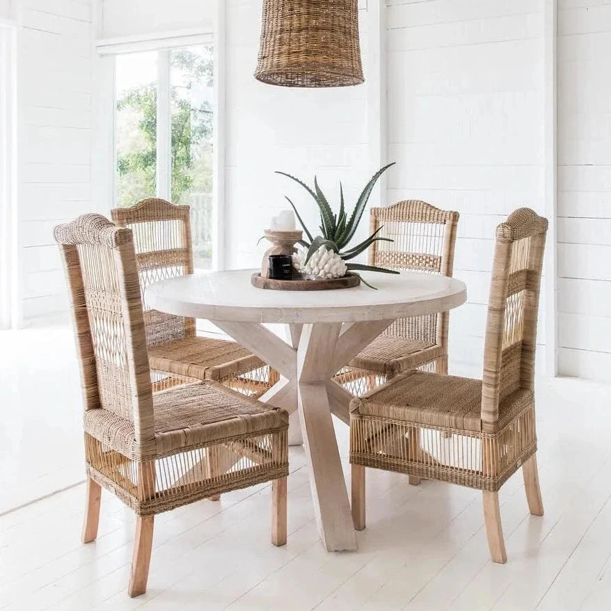 Dining area with round table and wicker chairs in a bright room.