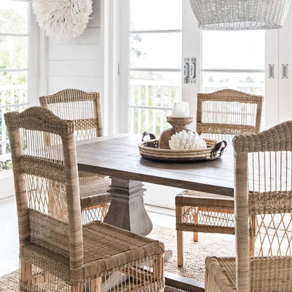 Dining room with wooden table and wicker chairs in a bright, sunlit room.