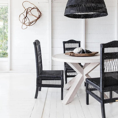 Dining area with black wicker chairs and a round table under a black woven pendant light.