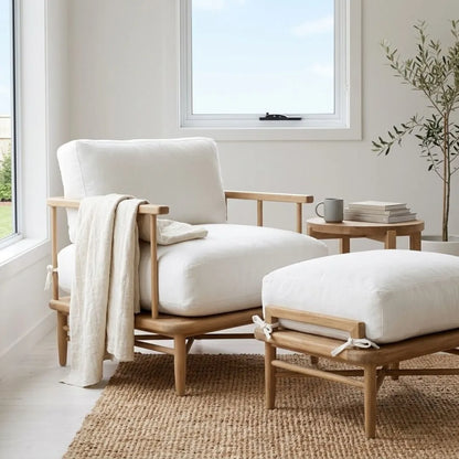 Wooden armchair with white cushions and a matching ottoman in a bright room.