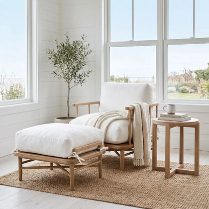 White armchair and ottoman with a plant and small table in a bright room.