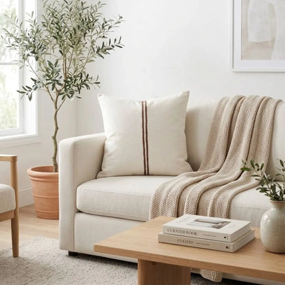Cozy living room with a beige sofa, throw blanket, and books on a wooden coffee table.