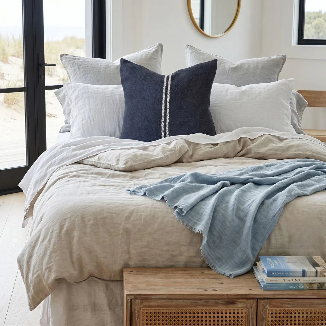 Neatly made bed with pillows and a blanket in a bright bedroom.