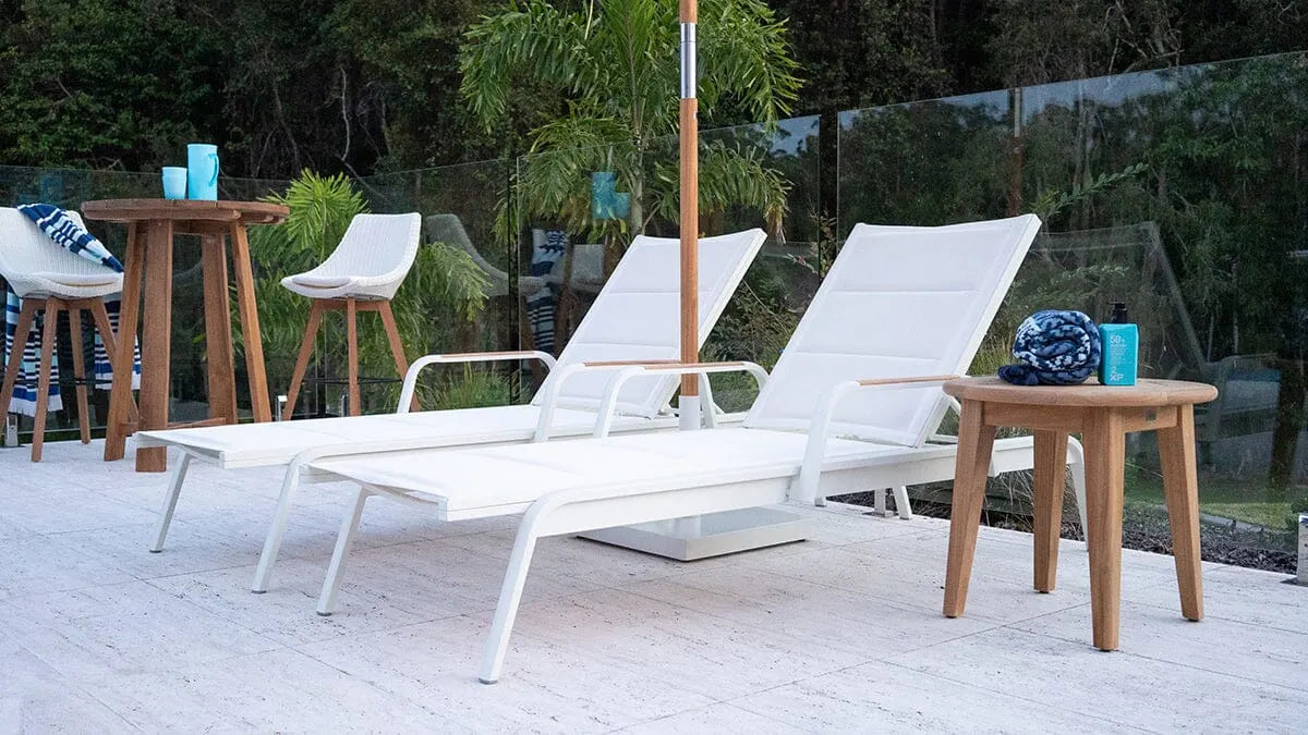 White lounge chairs on a patio with wooden tables and outdoor decor.