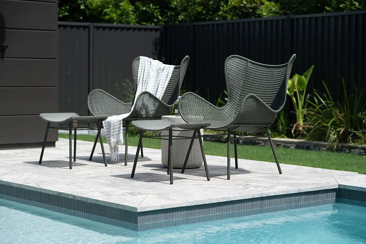 Outdoor patio set with chairs and a table by a pool