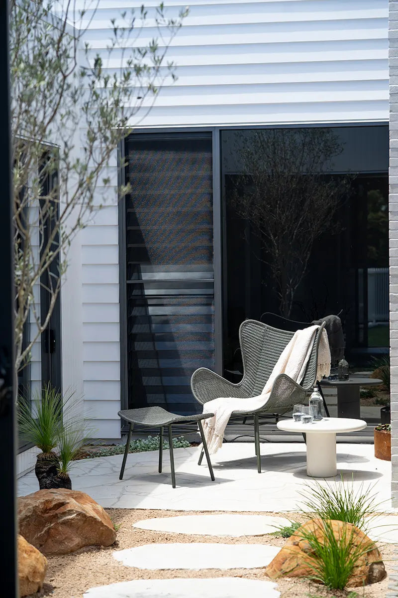Modern outdoor patio with chairs, table, and decorative elements.