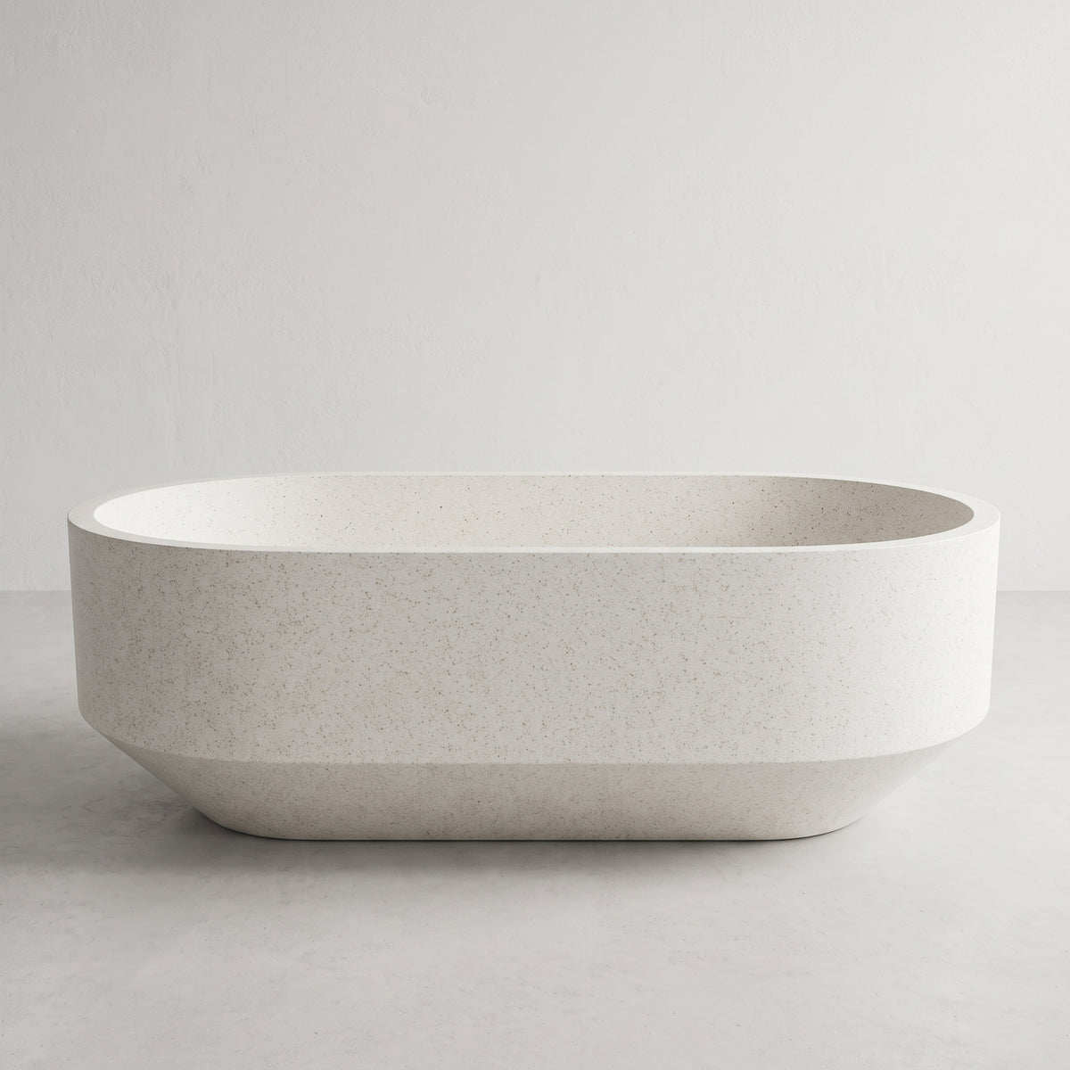 A modern oval freestanding bathtub in a light speckled stone or concrete finish, shown against a neutral light gray background.