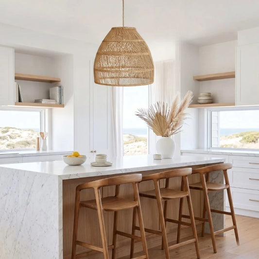 Modern kitchen with marble island, wooden stools, and wicker pendant light.