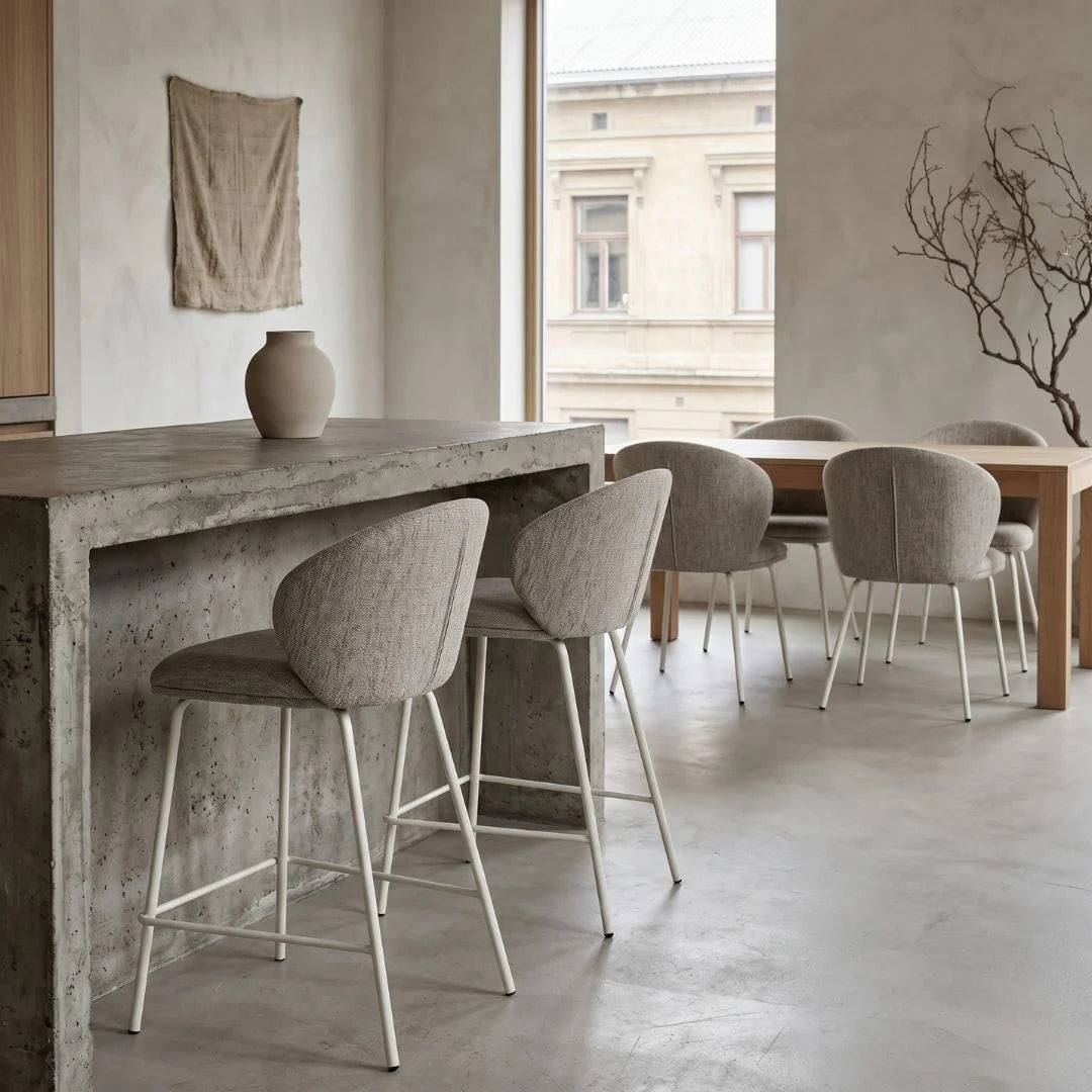 Modern dining area with concrete table and upholstered chairs in a neutral-toned room.