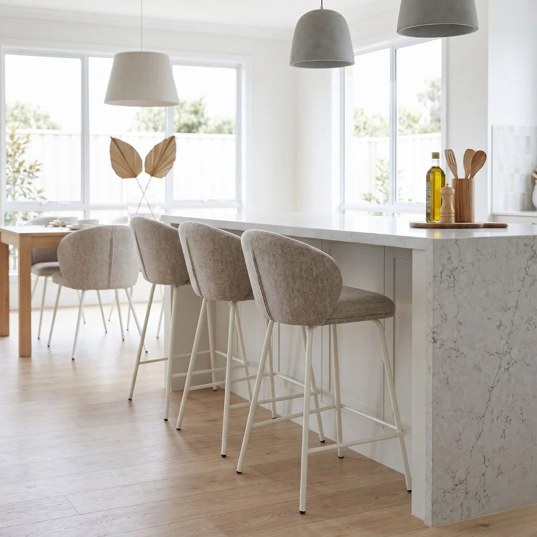 Modern kitchen with marble island, bar stools, and pendant lights.