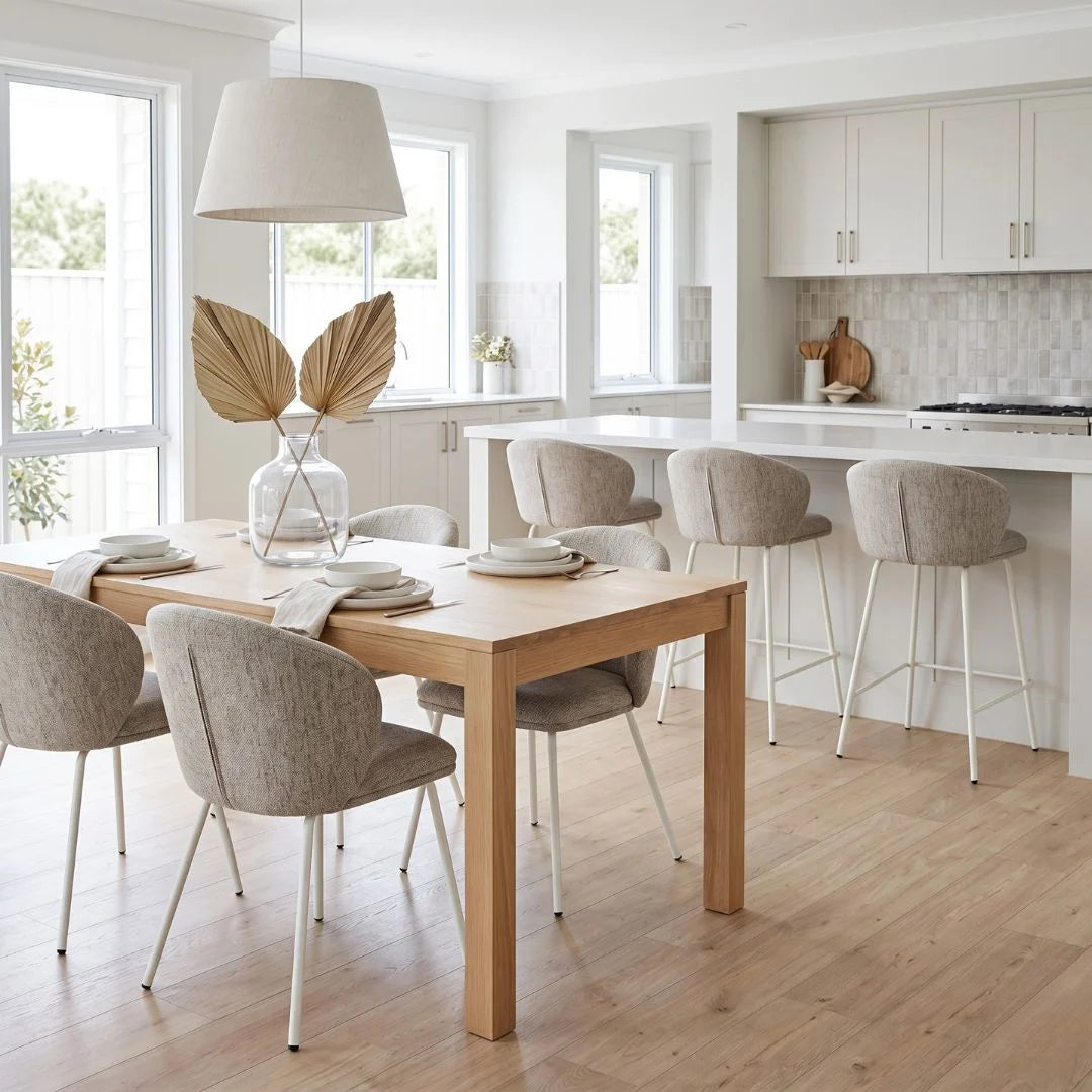 Modern kitchen with wooden dining table and chairs, white cabinets, and large windows.