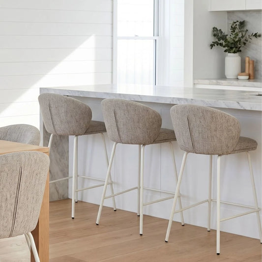 Three bar stools with beige seats and white legs in a kitchen setting.