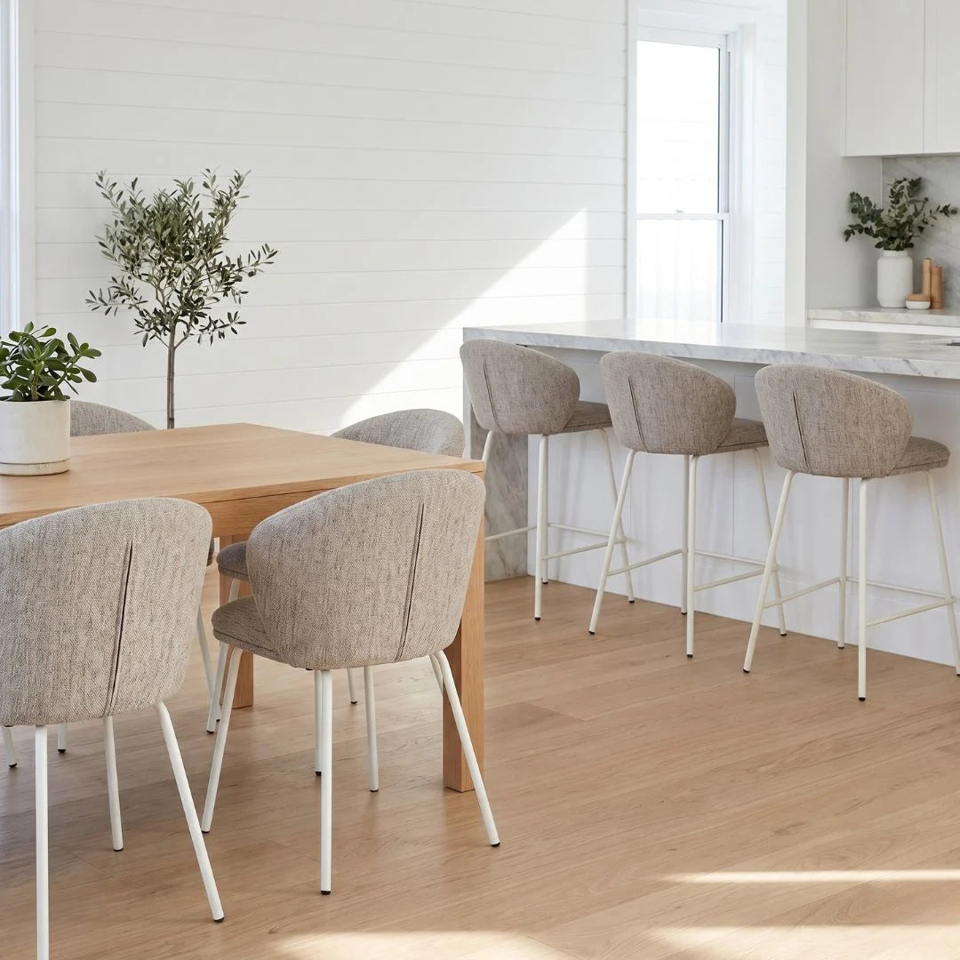 Modern kitchen with wooden dining table and stools, white walls, and natural light.